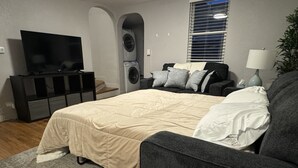 Een moderne slaapkamer met een bed, een televisie, een wasmachine en een bank.