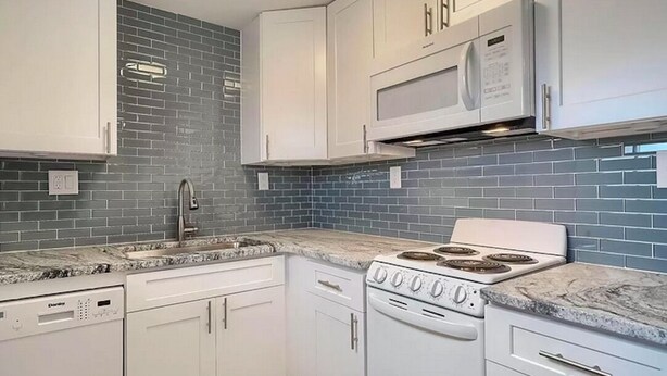 Een keuken met witte kasten, een magnetron, een fornuis en een vaatwasser.