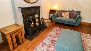 Una sala de estar acogedora con chimenea, un sofá azul y un banco de madera.