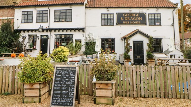 Un edificio de dos pisos con un letrero que dice 'George & Dragon Free House'.
