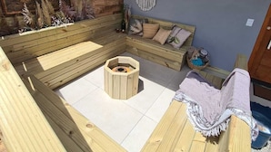 A cozy outdoor seating area with a wooden bench, a woven basket hanging from the ceiling, and a wall-mounted macrame piece. - Refúgio dos Coiotes (Cambara do Sul)