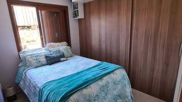 Un dormitorio con cama, armario de madera y ventana.