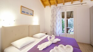 Habitación de hotel con cama, almohadas, un cuadro en la pared y una ventana con cortinas.