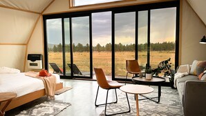 A spacious tent-style room with a bed, a round table, and two chairs. - Backland Luxury Nature Resort - Grand Canyon (Williams)