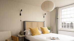 A hotel room with a large bed, a chair, a bedside table with a lamp, and a window with curtains. - Double Room with en-suite shower room in the Central Village Location of Hurstpierpoint (Hurstpierpoint)