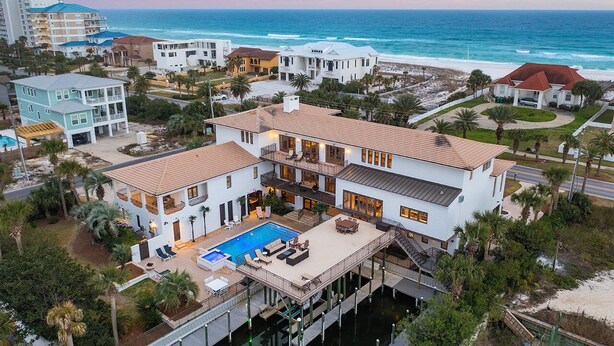 A large, two-story house with a pool, waterfront views, and a dock.