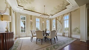A dining room with a chandelier, a round table, and six chairs.