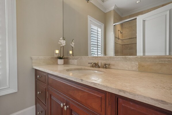 A bathroom with a large mirror, a sink, and wooden cabinetry.