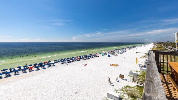 A beach with umbrellas and beach chairs, a wooden deck, and a view of the ocean. - Beachfront Bar! Restaurant on Site! Spa! Tennis! Beach Service Included! (Miramar Beach)