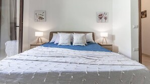Un dormitorio con cama, dos lámparas de noche y dos obras de arte florales colgadas en la pared.