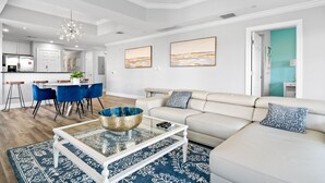 A modern living room with a sofa, coffee table, and dining area. - Condo with Golf Course Views | Near Attractions (Kissimmee)
