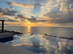 Relax by the serene pool, overlooking the calm sea and distant shoreline.