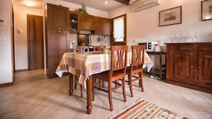 A dining area with a table set for four, wooden chairs, and a kitchen in the background.