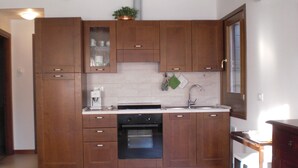 A kitchen with wooden cabinets, a built-in oven, a sink, and a microwave.