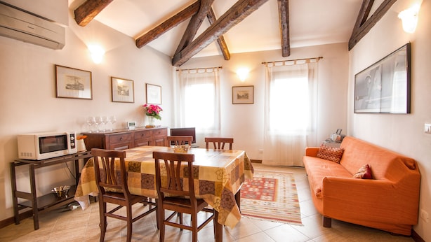 A dining area with a table and chairs, a kitchen area with a microwave, and a living room with a sofa.