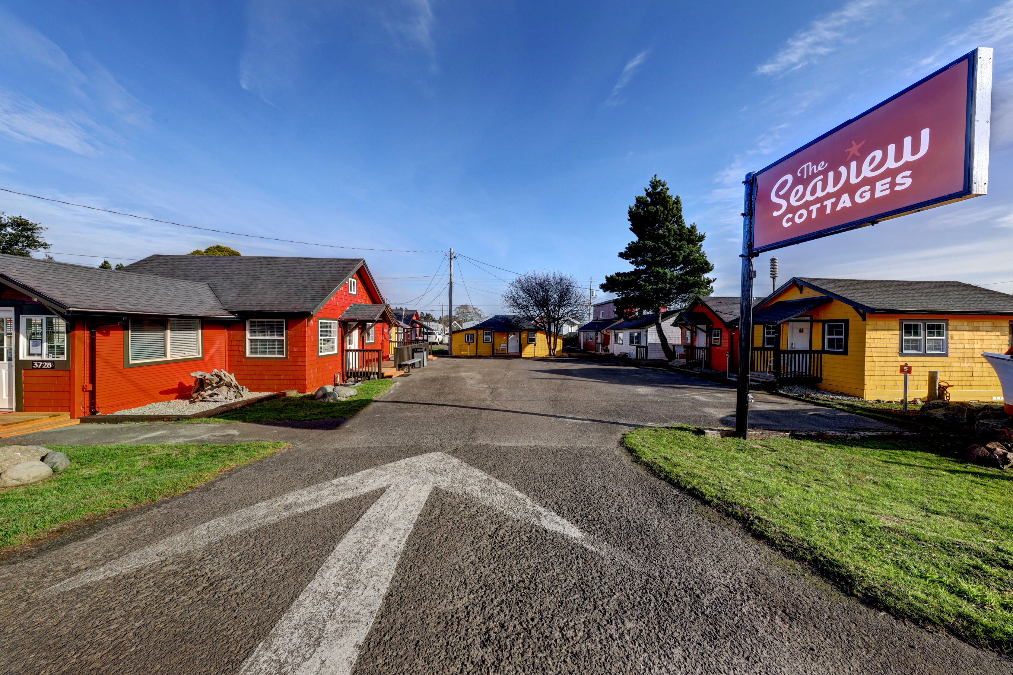 A row of cottages with a clear road in front, each with a distinct color and a sign for The Seaview Cottages.