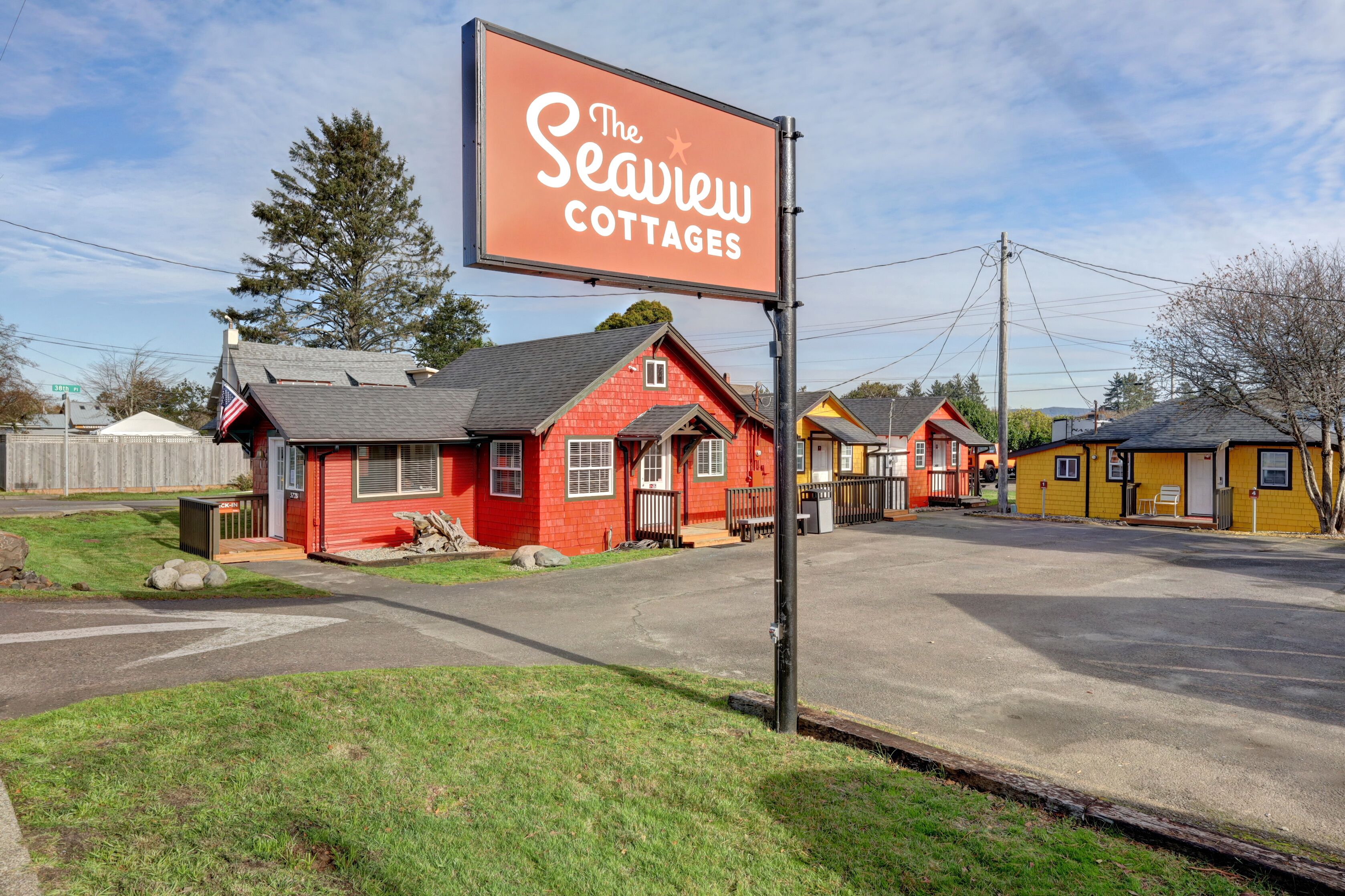 The Seaview Cottages with a red building and a yellow one, both with visible windows and a paved parking area.
