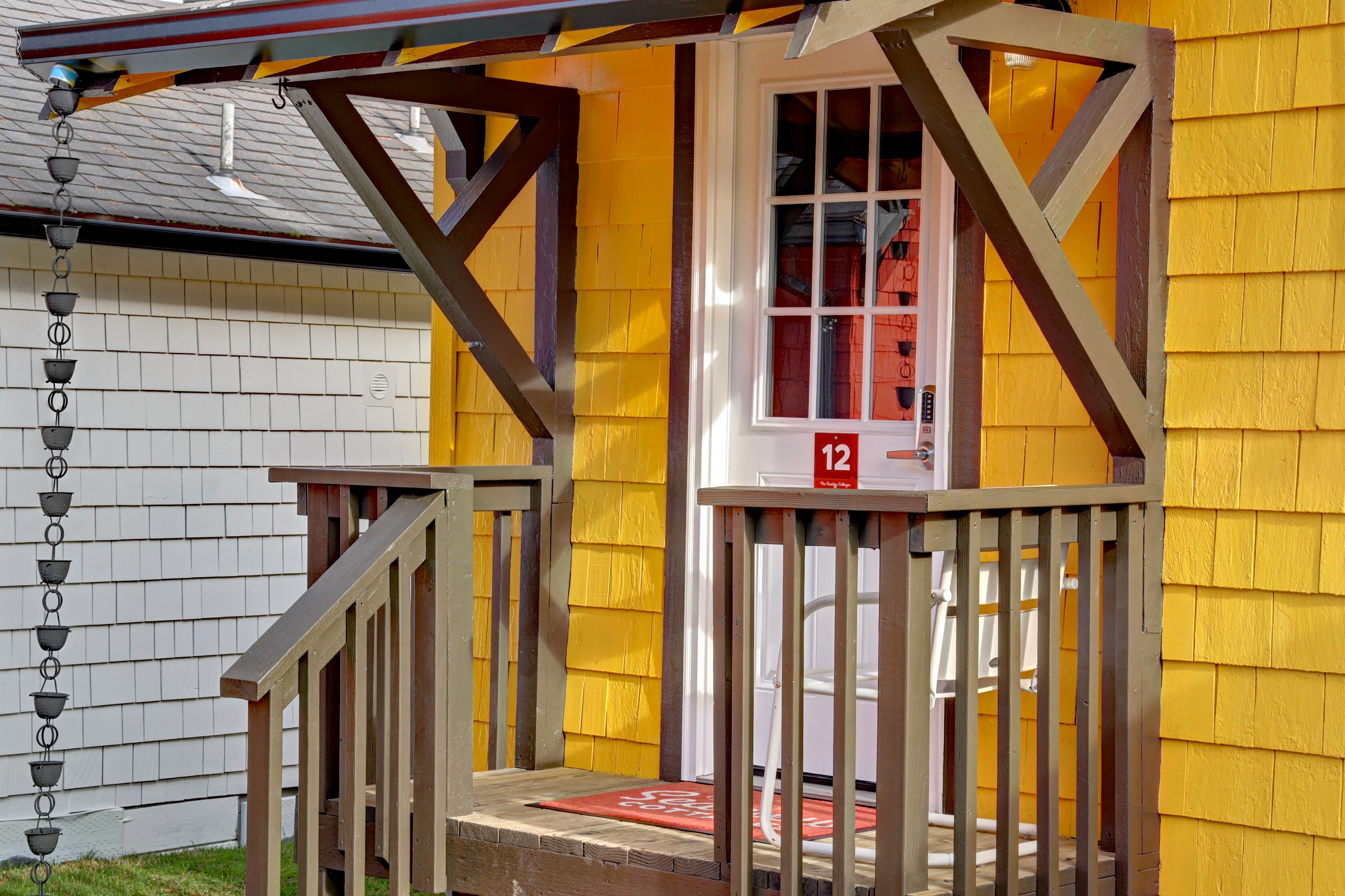 A yellow building with a wooden staircase leading to a door marked with the number 12.