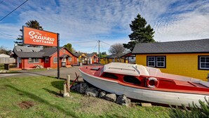 A row of colorful cottages with a sign for "The Seawrew Cottages" and a red and white boat parked in front.