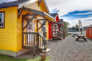 A yellow building with a wooden porch and picnic tables in a gravel area. - The Seaview Cottages (Seaview)