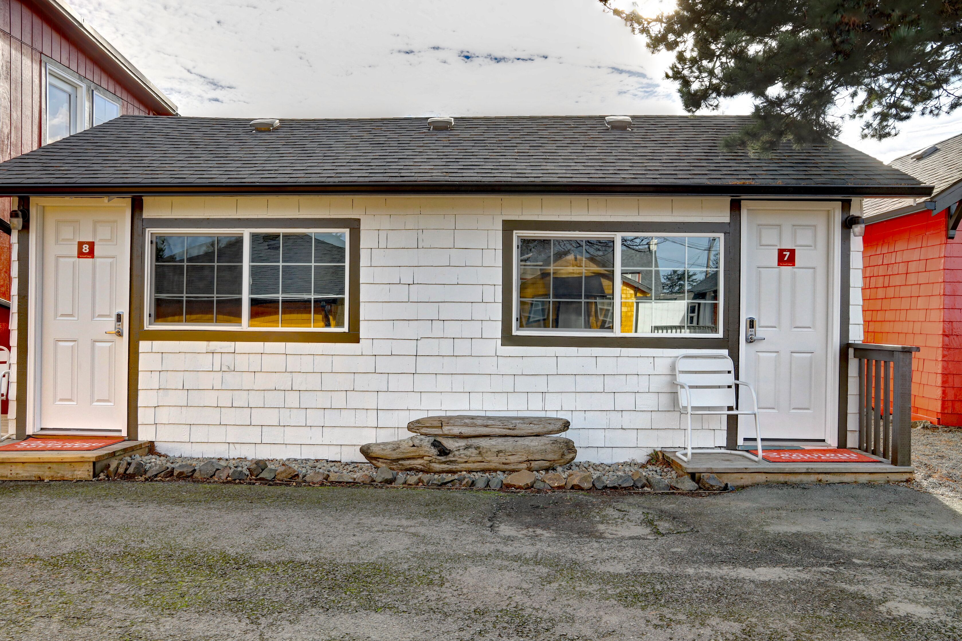 A small, single-story building with two doors marked with numbers 7 and 8, a garage door, and a small porch area with steps.