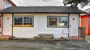 A small, single-story building with two doors marked with numbers 7 and 8, a garage door, and a small porch area with steps.