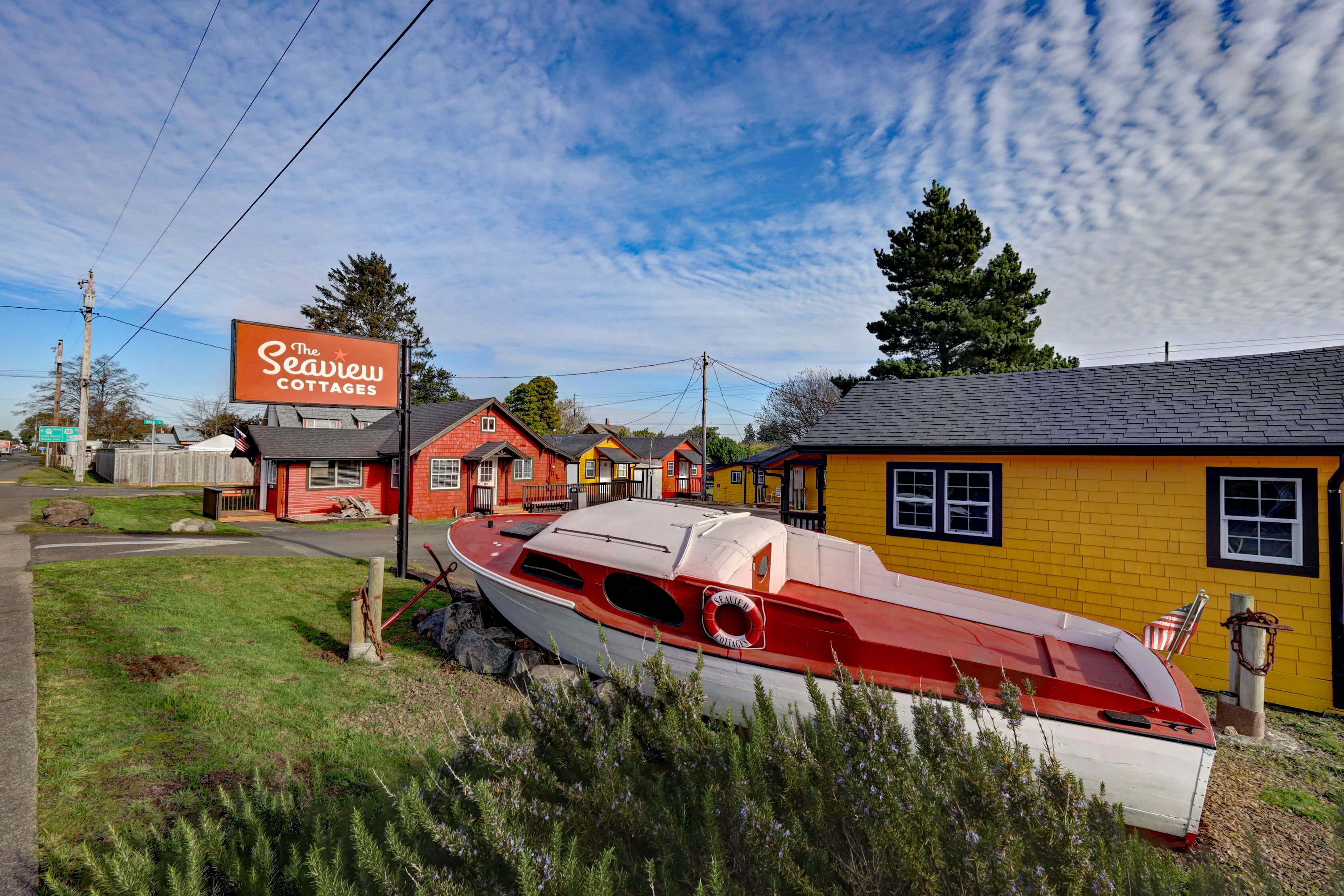 Los Cottages Seaview con un bote rojo y blanco al frente, rodeados de casas coloridas y un cielo despejado.
