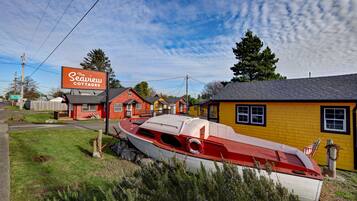Los Cottages Seaview con un bote rojo y blanco al frente, rodeados de casas coloridas y un cielo despejado.