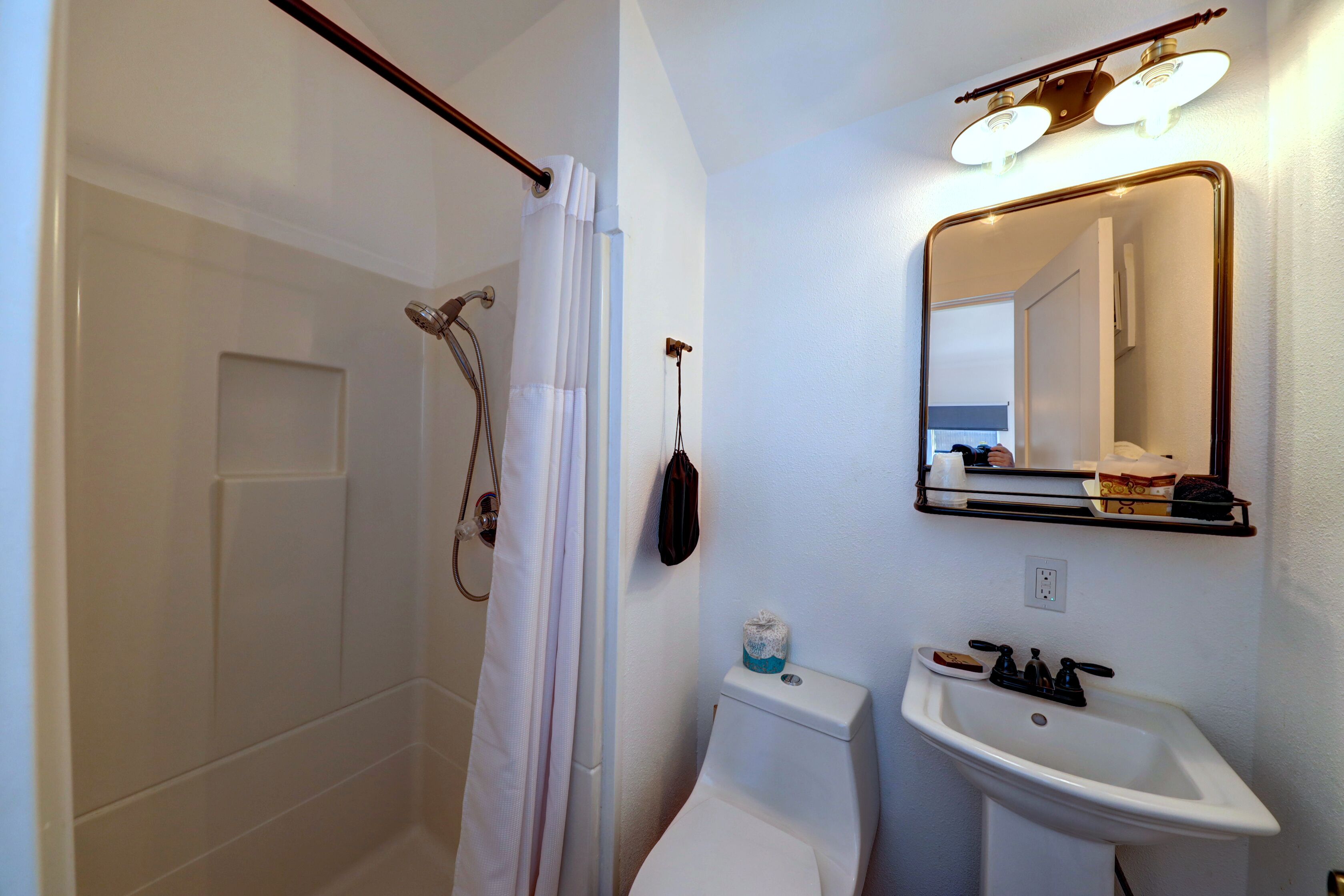 Un baño con ducha, inodoro, lavabo y espejo.