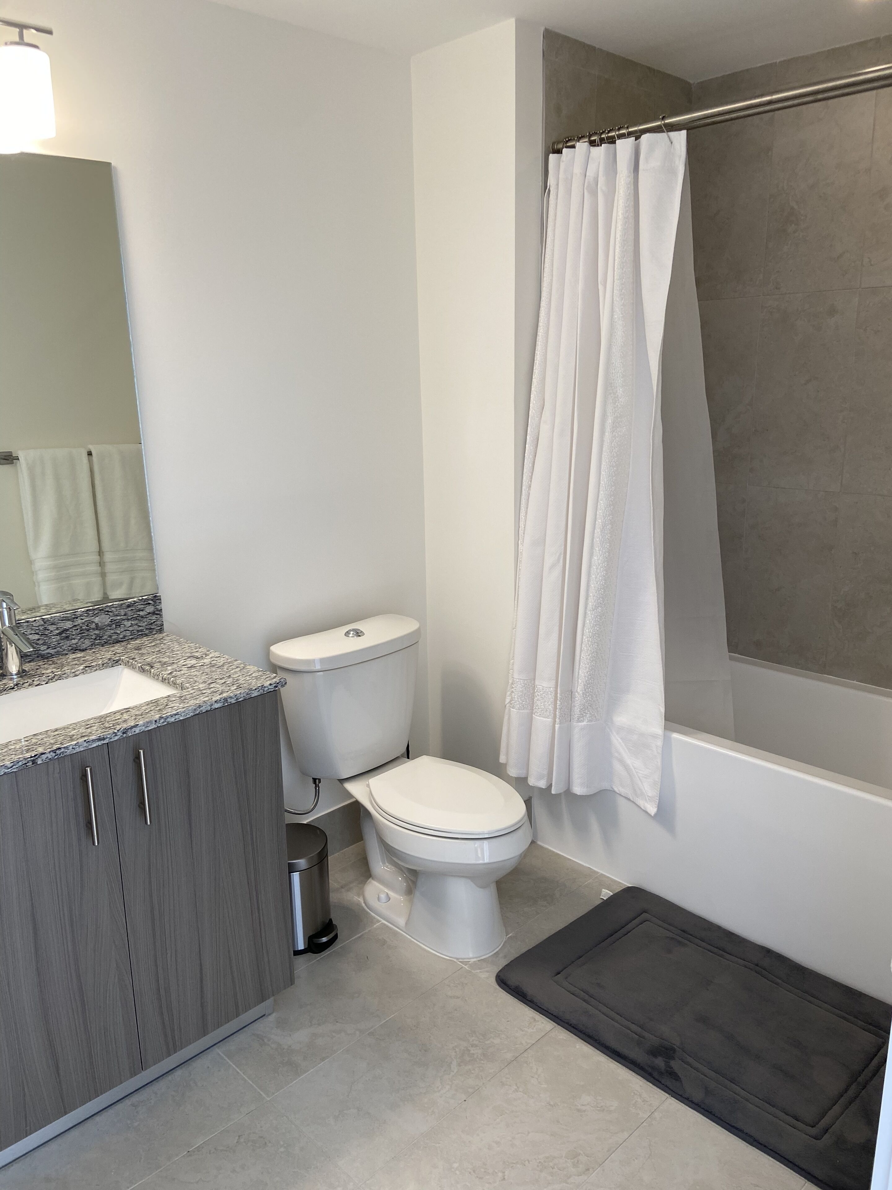 A modern bathroom with a toilet, sink, and shower curtain.