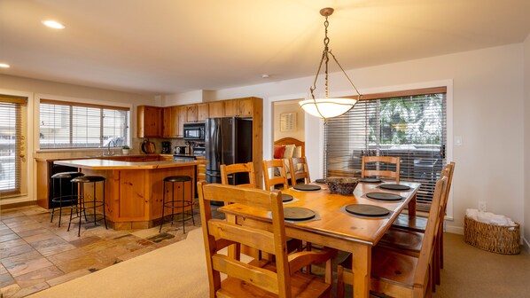 A modern kitchen with wooden cabinets, a central island, and a dining area with a wooden table and chairs.