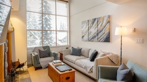 Ein Wohnzimmer mit einer Couch, Sesseln, einem Couchtisch und einem Gemälde an der Wand.