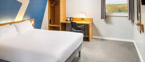 A hotel room with a bed, a desk, a chair, a wardrobe, and a window with a view.