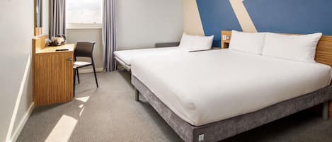Ein Hotelzimmer mit Bett, Schreibtisch, Stuhl und Blick zum Himmel.