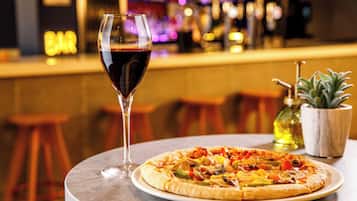 A pizza on a round table with a glass of red wine beside it.