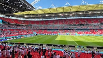 A stadium with multiple tiers of seating, a large open field, and a distinctive arch structure.