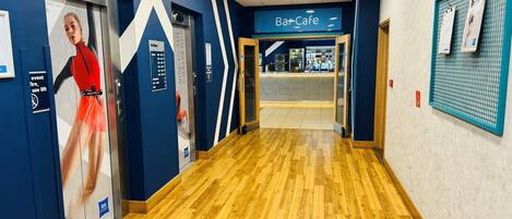A hallway with an elevator, a bar cafe, and a sign indicating the floor level.
