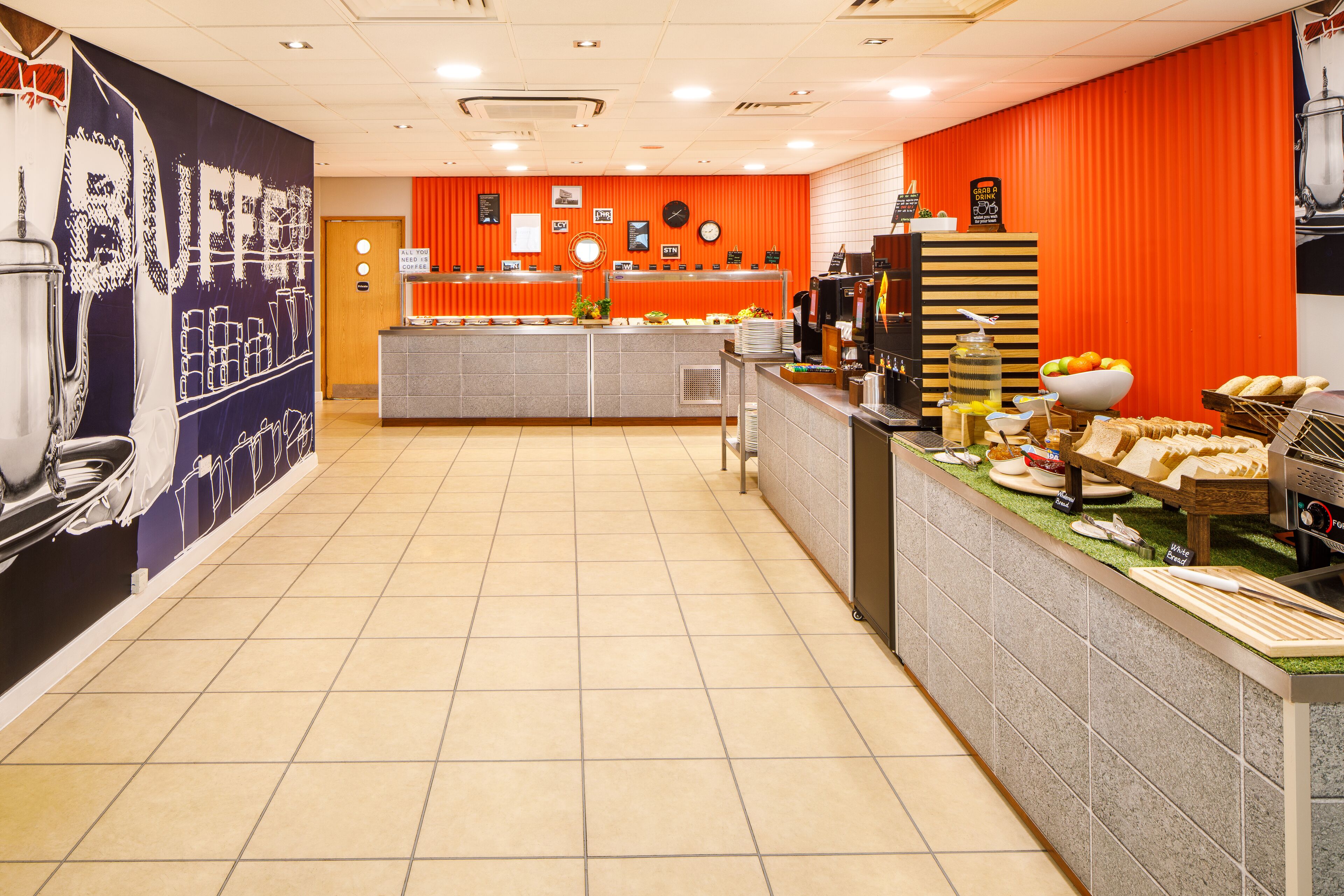 Zona de bufé con mostrador, exhibición de alimentos y una pared con un cartel grande.