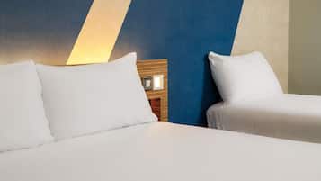 A hotel room with two beds, a wooden headboard, and a wall with a geometric pattern.
