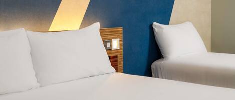 A hotel room with two beds, a wooden headboard, and a wall with a geometric pattern.