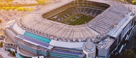 Vista aérea de un estadio con diseño circular, varios niveles y una zona urbana circundante.