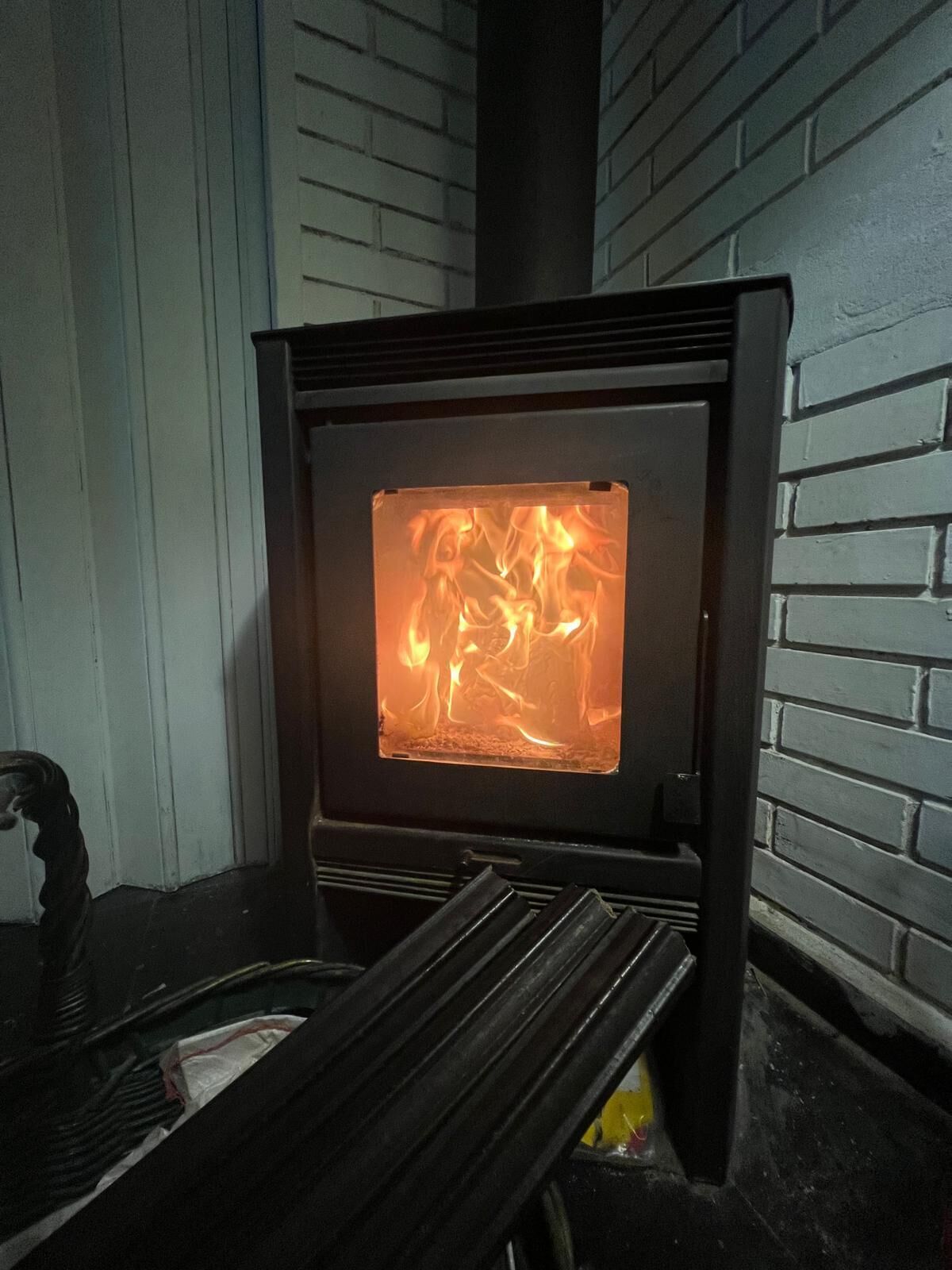 A wood-burning stove with a glass door, a black metal grate, and a chimney.