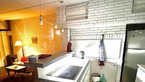 Een moderne keuken met een centraal eiland, witte bakstenen spatwand, roestvrijstalen apparatuur en hanglampen.