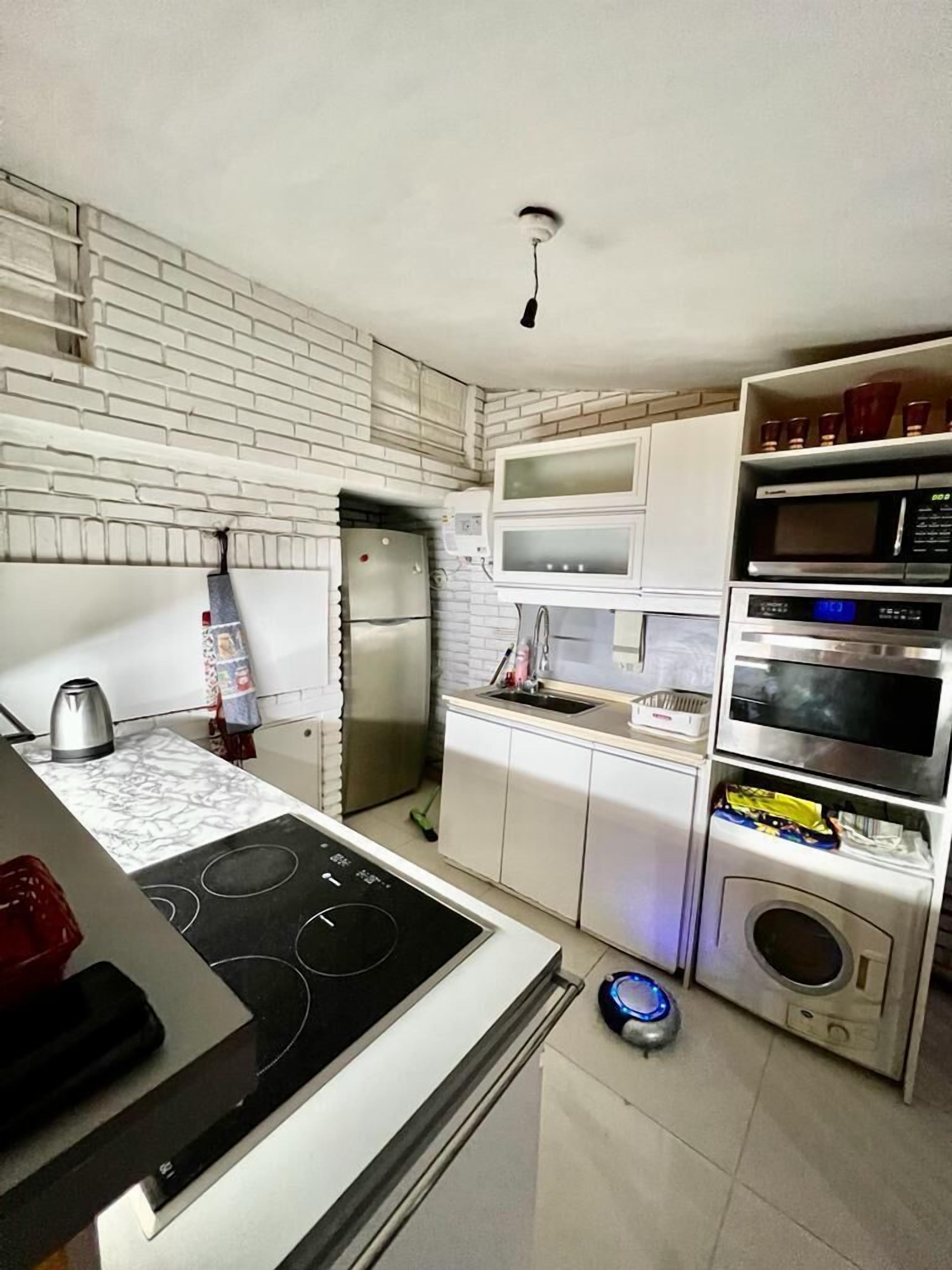 A modern kitchen with white cabinetry, a built-in stove, a refrigerator, and a microwave.