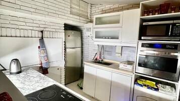 A modern kitchen with white cabinetry, a built-in stove, a refrigerator, and a microwave.