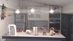 Een moderne keuken met een centraal eiland, hangende lampen, een magnetron en een koelkast.