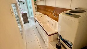 Een kleine badkamer met een bad, toilet en wasmachine.