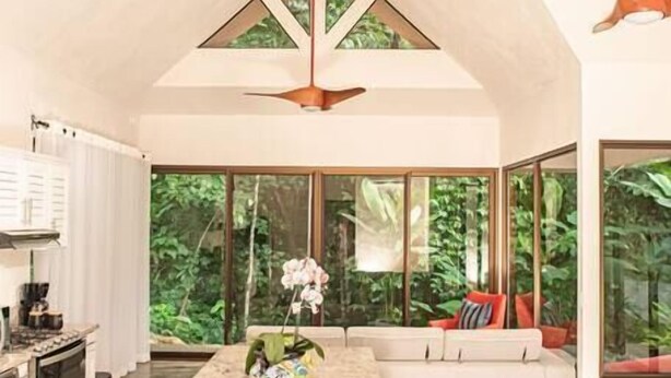 Una cocina amplia con una isla grande, ventanas amplias y un ventilador de techo.