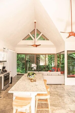 A spacious kitchen with a long island, large windows, and a ceiling fan.