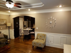 A living room with a dining area, wooden flooring, a patterned armchair, a ceiling fan, recessed lighting, and a wall clock. - Charming Modern Home near downtown Atlanta (Atlanta)